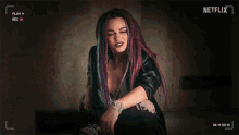 a woman with dreadlocks is sitting in front of a netflix logo