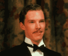 a man in a tuxedo with a bow tie looks at the camera