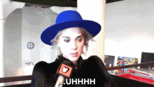 a woman wearing a blue hat is talking into a microphone and says " uhhhh "