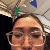 a woman wearing glasses is making a face in front of a tent .