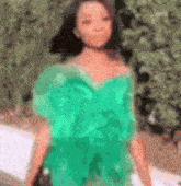 a woman in a green dress is standing in front of a tree .