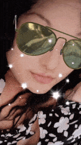 a woman wearing green sunglasses and a black and white floral dress