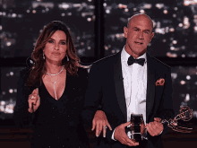 a man in a tuxedo and a woman in a black dress stand next to each other