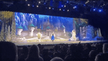 a group of people are sitting in front of a stage with a castle on it