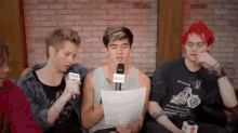 a group of young men are sitting on a couch and one of them is holding a nova microphone