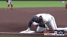 a baseball player kneeling on the base during a game between michigan and usc