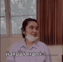a girl wearing a face mask is sitting in front of a window .