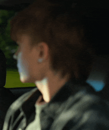 a young man is sitting in the back seat of a car looking out the window .