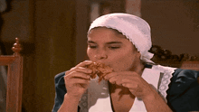 a woman in a white apron is eating a piece of food