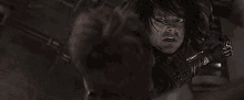 a man with long hair is holding a sword and looking at another man .