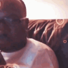 a man is sitting on a couch wearing a baseball cap and sunglasses .