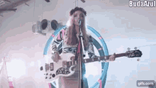 a woman is playing a white guitar and singing into a microphone .