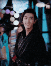 a man in a black kimono is smiling in front of a crowd