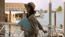 a woman in a hat and sunglasses is holding a blue folder with the name joseph wilky on it