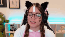 a girl wearing glasses and cat ears is sitting in a chair with her eyes closed .