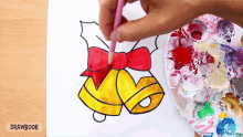 a person is painting a christmas bell with a bow