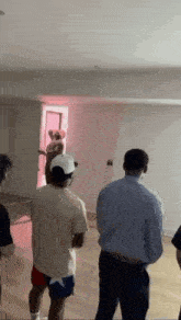 a group of people are standing in a room with a pink light on the ceiling .