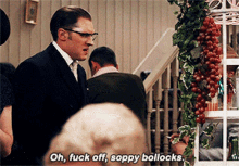 a man in a suit says oh fuck off soppy bollocks in front of a bunch of people