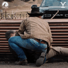 a man in a cowboy hat is kneeling down in front of a paramount sign