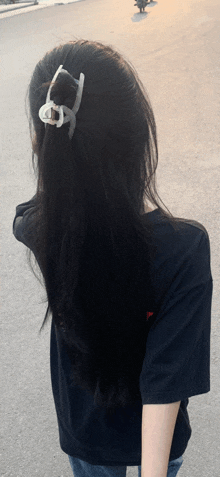 a woman with long black hair wearing a black shirt and a hair clip