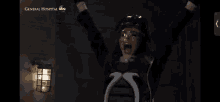 a screenshot of a tv show called general hospital shows a woman screaming with her arms in the air