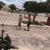 two men are fighting in a dirt field with a motorcycle parked in the foreground