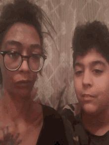 a woman wearing glasses is kissing another woman 's cheek
