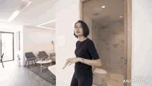 a woman in a black shirt is standing in a room with the words made in animatica on the bottom right