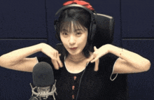 a woman wearing headphones and a red headband is making a face in front of a microphone