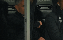 a man wearing a jacket that says np sits in a recaro seat