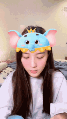 a woman wearing a blue elephant mask with a crown on top