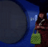 a woman with a green purse is standing in front of a projection of a full moon