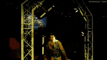 a wrestler is walking through a tunnel with a survivor logo on the wall behind him