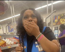 a woman covering her mouth with her hands in a grocery store aisle