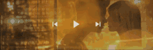 a man in a hat is standing in front of a fire with a play button .