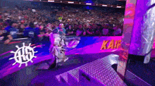 a person in a mask is walking down a ramp in front of a crowd at a wrestling event .