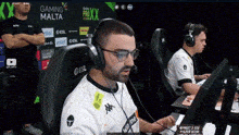 a man wearing headphones is sitting in front of a gaming malta banner