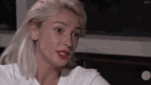 a woman with blonde hair and red lips is wearing a white t-shirt