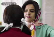 two women are standing next to each other and one of them is wearing a scarf around her head .