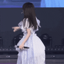 a woman in a white dress holds a microphone