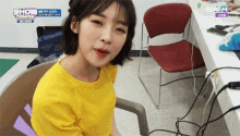a girl in a yellow shirt is sitting in a chair in front of a screen that says show champion on it