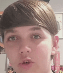 a close up of a young boy 's face with a can of monster energy drink in the background