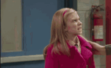 a girl in a pink coat is dancing in a hallway next to a man in a brown jacket