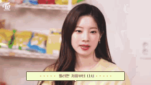 a woman in a yellow shirt is standing in front of a shelf with snacks .