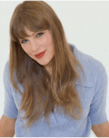 a woman with long hair and red lipstick is wearing a light blue polo shirt .