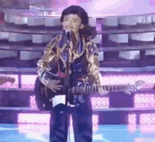 a man is singing into a microphone while playing a guitar on stage .