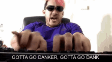 a man with pink hair and sunglasses is typing on a keyboard and making a funny face .