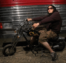 a man is sitting on a small motorcycle with a flame on the tank