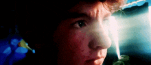 a close up of a young boy 's face with a light shining on his face .