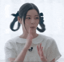 a woman with pigtails on her hair is wearing a white shirt and a microphone .